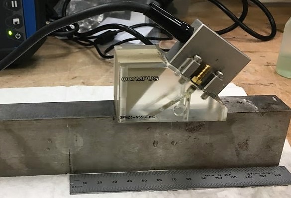 Olympus phased array probe and Rexolite wedge on an ASTM E1820 fracture toughness testing standard