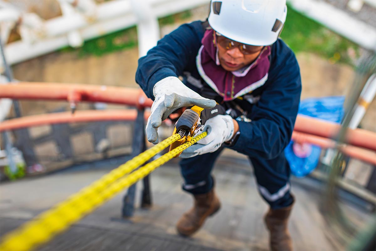 Travailleur escaladant un réservoir et utilisant une méthode d’inspection en accès sur cordes pour effectuer des mesures d’épaisseur