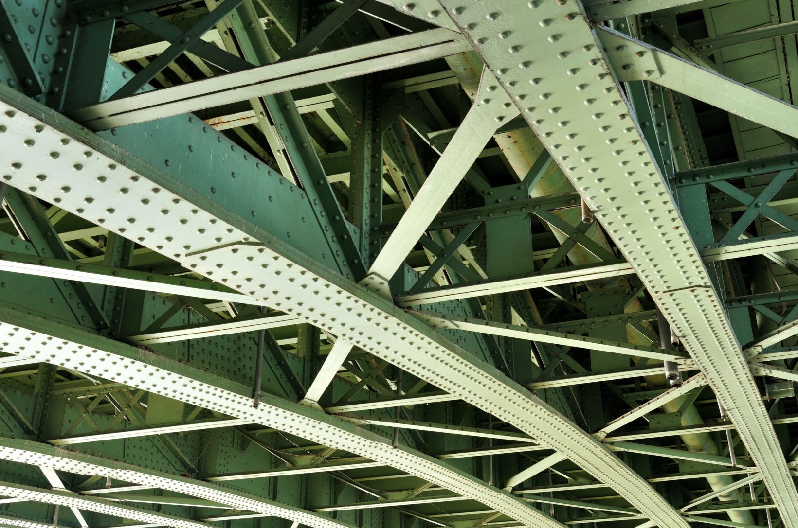 Detailní záběr na nosníky ocelového mostu, které představují části mostní struktury, které jsou vystaveny cyklické zátěži